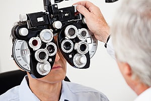 an ophthalmologist using a phoropter during an eye exam